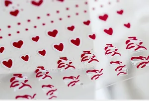 Macro view of red heart and wave pattern nail art stickers on a white display block