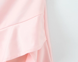 Close-up detail of pink dress featuring layered ruffle hem and smooth fabric texture