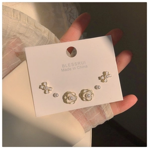 Close-up of elegant pearl camellia and golden bow earring set with vintage French style