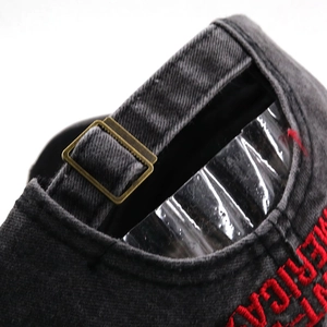 Detail of adjustable brass buckle and red embroidered text on a dark gray baseball cap