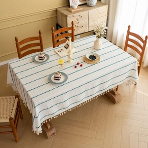 White and green striped tablecloth with tassel fringe on a rectangular wooden dining table