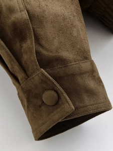 Détail du poignet d'une veste en daim marron foncé avec un bouton recouvert de tissu