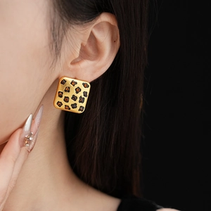 Close-up of vintage golden leopard print square earrings worn on a model with black backdrop