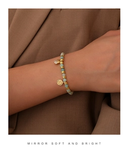 Detail of light green stone beaded bracelet with shell charm and gold finish