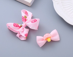 Detail of pink fabric strawberry hair clip and mushroom bow set for girls on a plate