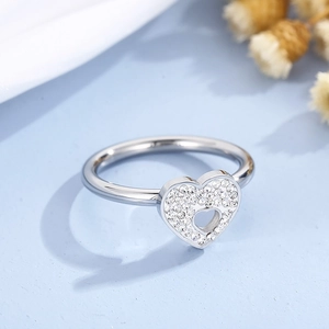 Close-up of silver hollow heart-shaped ring with pavé-set crystals on blue background