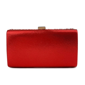 Detail of red clutch bag with metallic finish, gold clasp, and beaded trim top edge