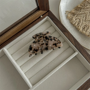 Detail of light leopard print acetate hair claw with rhinestones in a wooden gift box