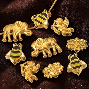 Golden DIY jewelry pendants with elephant, bee, cupid, and flower shapes on brown fabric