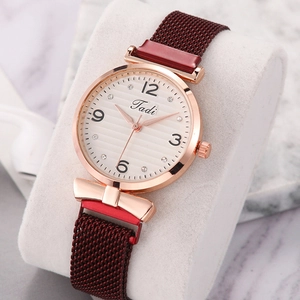 Macro view of burgundy Milanese strap with magnetic clasp and rose gold case watch