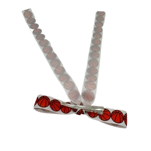 Close-up of white ribbed bow hair clip featuring red basketball patterns and metal clip