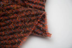 Macro shot of thick herringbone tweed fabric in orange, brown and navy blue wool blend