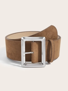 Gros plan sur une large ceinture en daim marron avec une grande boucle en métal argenté
