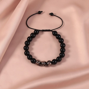 Detailed shot of black beaded adjustable bracelet with galaxy beads on pink satin fabric