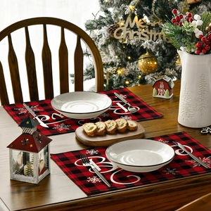 Close-up of red and black buffalo plaid Christmas placemat with white Believe text and snowflakes