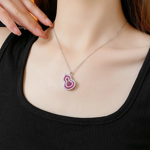 Close-up of a silver hollow gourd pendant necklace with red and clear zircon stones