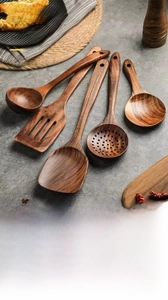 Set of five handmade teak wood kitchen utensils showing natural grain and hanging holes