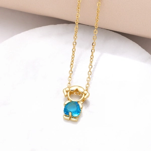 Detail of gold girl pendant with blue heart zircon on white marble and velvet