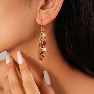 Close-up of tassel earrings with colorful glass beads and star chains on model