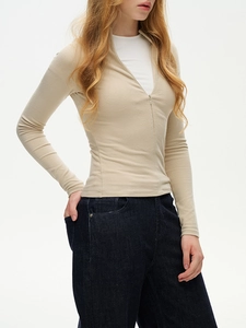 Detail of beige zip-up slim fit mock neck thermal top showing fabric texture and zipper