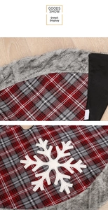 Close-up of red plaid Christmas tree skirt with white snowflake and gray faux fur trim