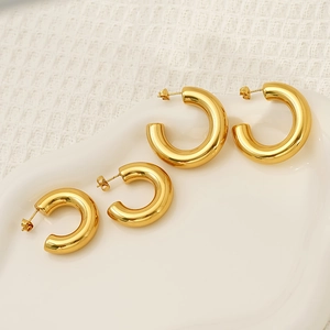 Polished gold plated C-shape hoop earrings in two sizes on minimalist ceramic tray