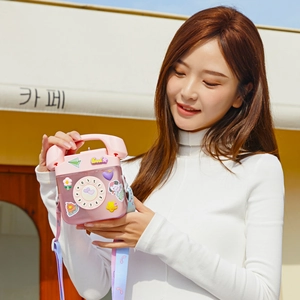Pink telephone shaped water bottle with strap shown in an outdoor cafe lifestyle setting