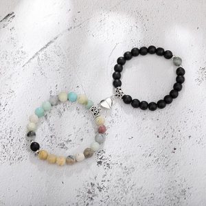 Close-up of magnetic heart clasp connecting natural stone and matte black bead bracelets