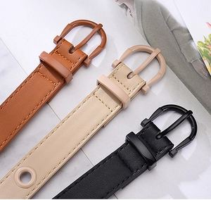 Detail of candy-colored faux leather belts in brown, beige, and black with round buckles