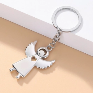 Polished silver angel keychain with hollow heart and wings on a geometric display