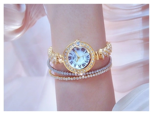 Detail of luxury gold watch with rhinestones and Roman numerals on woman wrist
