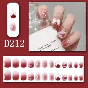 Detail of red gradient press-on nails with 3D bows, pearls and marble patterns