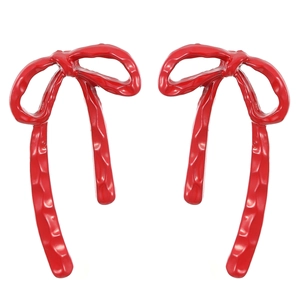 Detail shot of oversized red bow earrings with hammered texture and glossy finish