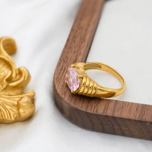 Macro detail of 14K gold ring with pink oval gemstone and inner band hallmark