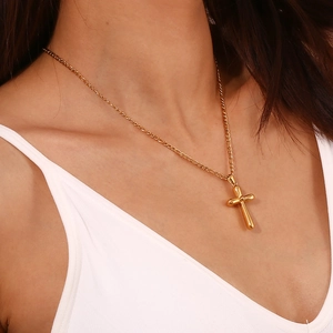 Close-up of a minimalist 18K gold plated stainless steel cross necklace on a model