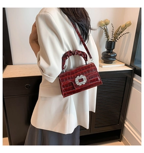 Detail of reddish brown crocodile texture bag with crystal buckle and ruched handle