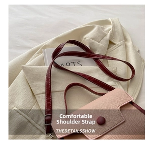 Close-up of pink textured faux leather handbag with red shoulder strap and white stitching