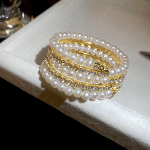 Close-up of double-layer pearl bangle with gold rhinestones on beige velvet