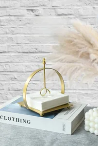 Detail of gold metal napkin holder with a glass ball weight in a modern home setting