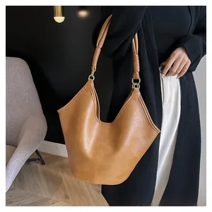 Detailed view of brown leather tote bag featuring a unique V-shaped opening and round handles