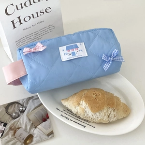 Nahaufnahme einer blauen gesteppten Tasche mit rosa karierter Schleife und Griff