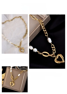 Close-up of golden necklace featuring irregular pearls and a hammered heart pendant