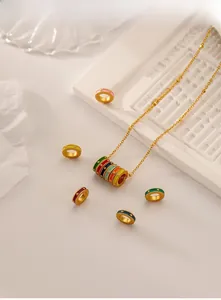 Macro detail of colorful enamel rings and gold bead chain on white plaster tray