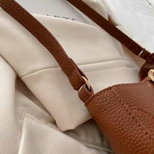 Close-up of brown litchi pattern leather shoulder bag with neat stitching and metal ring