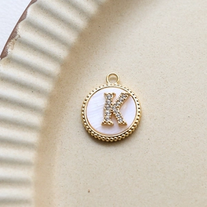 Detailed view of gold plated round shell pendant with micro-pave zircon letter K