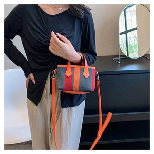 Detail of striped canvas mini bag with orange accents and detachable shoulder strap