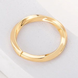 Close-up of minimalist gold twisted ring with high-polished mirror finish surface