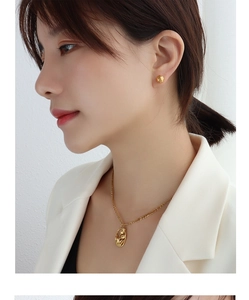 Gros plan du mannequin portant collier tulipe et boucles d'oreilles boules en or 18k