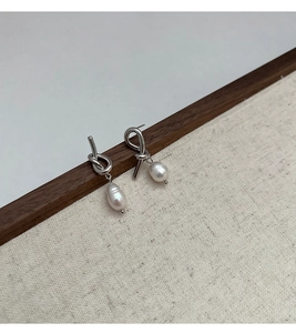 Detail view of silver knot earrings with natural freshwater teardrop pearls on canvas