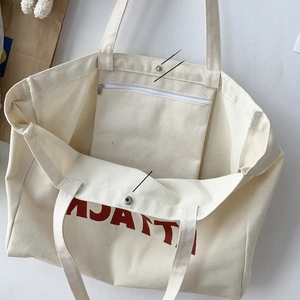 Detail of canvas tote bag showing inner zippered pocket and magnetic snap closure